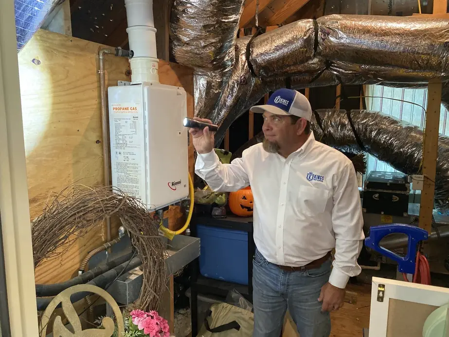 A King's Pest Control technician checking an opened utility run with a flashlight